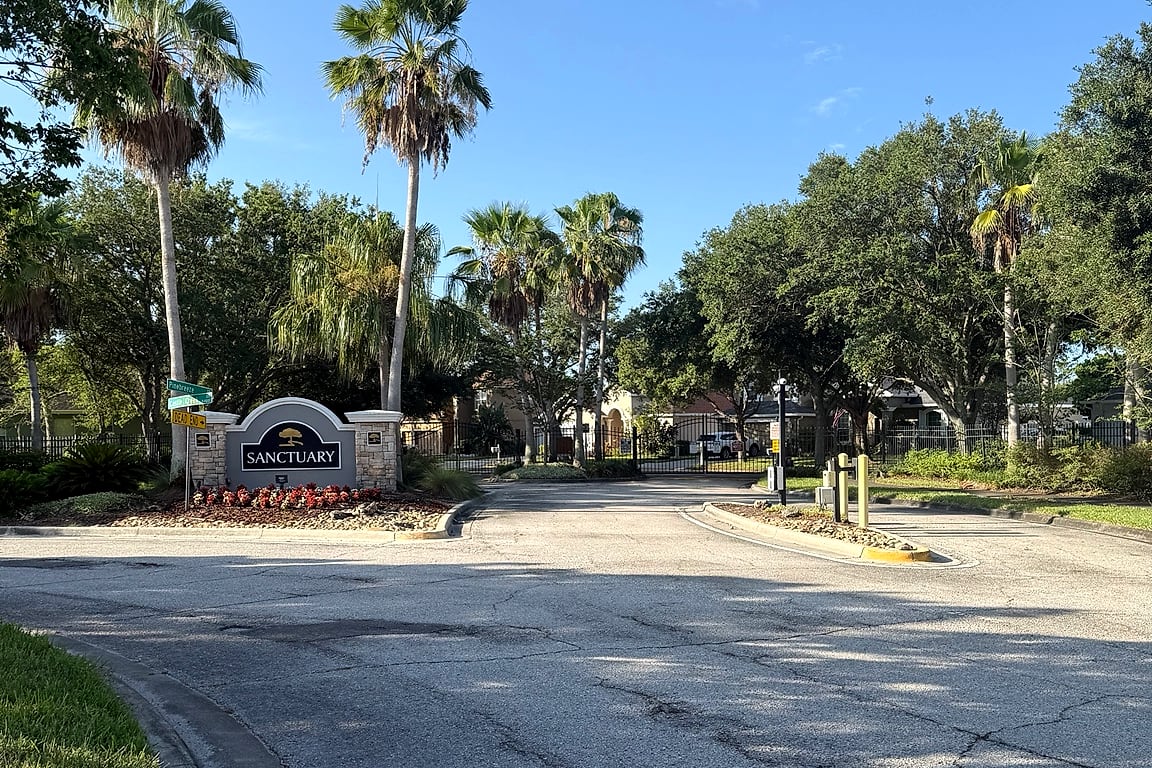 The tree-lined, gated entrance approach to the Sanctuary at Oak Creek community